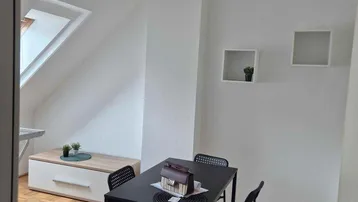 Heller Essbereich im Dachgeschoss mit Schrägdach, Parkettboden und modernem Esstisch.