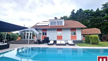 Großzügiger Außenbereich mit Swimmingpool, Liegeflächen und Blick auf das Haus mit Solaranlage.