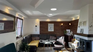Gemütliches Wohnzimmer mit Kamin, dunklem Sofa und indirekter Beleuchtung.