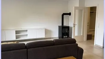 Wohnzimmer mit modernem Holzofen, Sofa und weißem Sideboard.