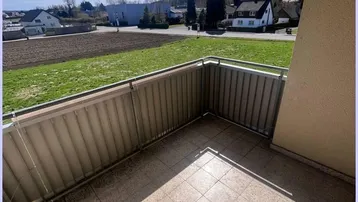 Geräumiger Balkon mit Fliesenboden und Markise, bietet einen weiten Blick ins Grüne.