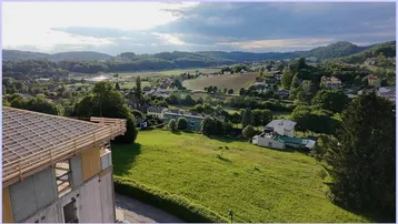 Blick auf ein im Bau befindliches Gebäude mit weitem Ausblick über eine grüne Hügellandschaft.