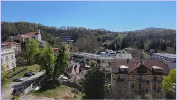 Panoramablick über eine malerische Stadt mit historischen Gebäuden und grünen Hügeln im Hintergrund.