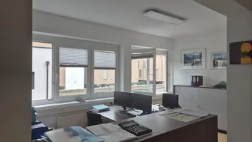 Helles Büro mit mehreren Arbeitsplätzen, großen Fenstern und Blick auf die Umgebung.