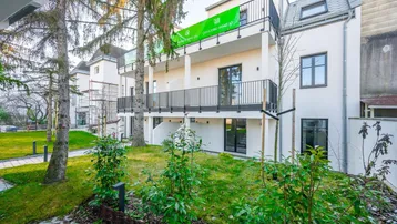 Neubau-Mehrfamilienhaus mit modernen Balkonen und gepflegter Grünanlage.