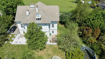 Luftaufnahme des Hauses mit großem Garten, gepflasterten Bereichen und ländlicher Umgebung.