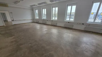 Geräumiger, leerer Büroraum mit mehreren Fenstern und einfacher Beleuchtung, bereit zur individuellen Gestaltung.