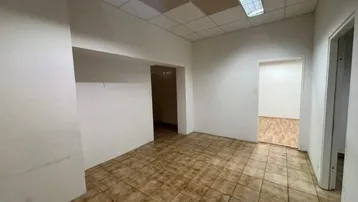 Leerer Büroraum mit braunen Fliesen und abgehängter Decke, bereit zur Renovierung.