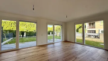 Helles Wohnzimmer mit Holzboden und großen Schiebetüren zum Garten.