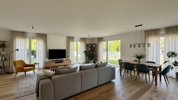 Helles, offenes Wohn- und Esszimmer mit Holzboden, modernen Möbeln und Zugang zum Garten.