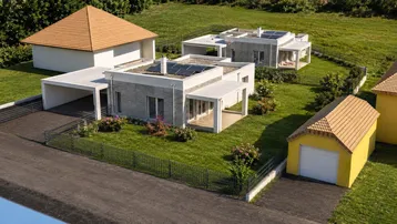 Moderne Häuser mit Flachdächern, Solaranlagen und Betonfassaden, umgeben von grünen Rasenflächen und einem gelben Nebengebäude.