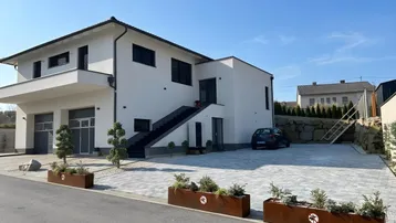 Modernes Einfamilienhaus mit weißer Fassade, Doppelgarage und gepflasterter Einfahrt.
