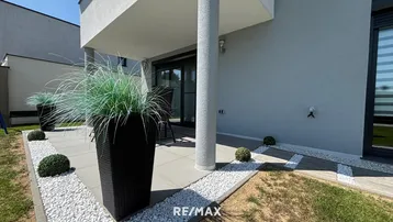 Moderne Terrasse mit Sitzgelegenheiten und dekorativen Pflanzen, umgeben von einem gepflegten Gartenbereich.