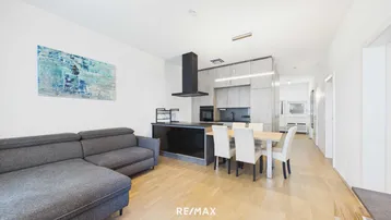 Moderner offener Wohn-Essbereich mit integrierter Küche, Sofa und Esstisch.
