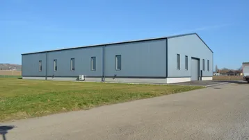 Modernes Industriegebäude mit blauer Metallfassade und weitem Blick über die Landschaft unter klarem Himmel.