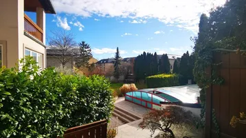 Weitläufiger Blick über den Garten mit überdachtem Pool und der umliegenden Wohngegend.