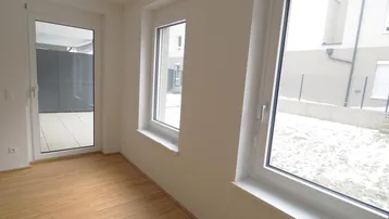 Helles Zimmer mit Parkettboden und Zugang zu einer Terrasse oder Loggia, ideal für Neubau.
