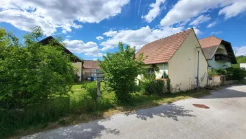 Ländliches Anwesen mit mehreren Gebäuden unter blauem Himmel und grüner Umgebung.