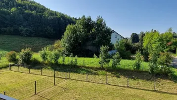 Weitläufiger Blick vom Balkon auf die grüne Hügellandschaft und die Umgebung.