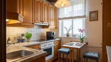 Gemütliche Küche mit Holzschränken, Fliesenrückwand und kleinem Esstisch am Fenster.