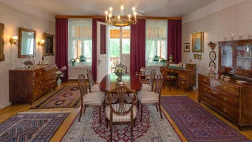 Elegantes Esszimmer mit klassischem Holztisch, antiken Möbeln und Zugang zu einem Balkon.