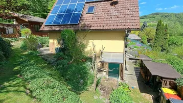 Rückseite des Hauses mit Photovoltaikanlage auf dem Dach und großem Gartenbereich.
