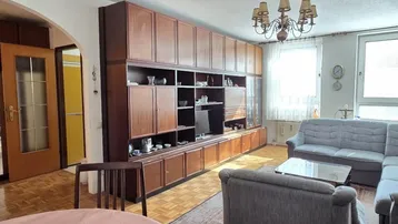 Helles Wohnzimmer mit großer Schrankwand, Parkettboden und gemütlicher Sitzecke.