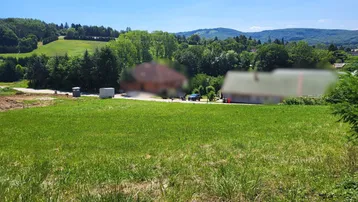 Weitläufiges grünes Grundstück mit Blick auf die umliegende Landschaft und entfernte Häuser.