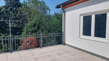 Große geflieste Terrasse mit schmiedeeisernem Geländer und weitem Blick ins Grüne.