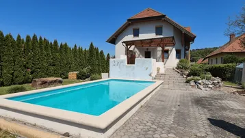 Einfamilienhaus mit privatem Swimmingpool im Garten unter blauem Himmel.
