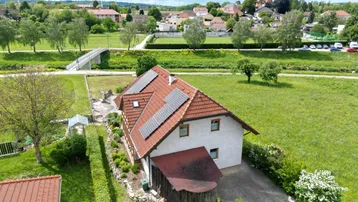Luftaufnahme des Hauses mit Solaranlage auf dem Dach und grüner Umgebung.