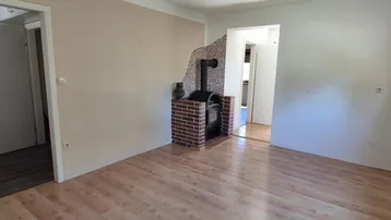 Wohnzimmer mit Laminatboden, hellem Anstrich und einem gemauerten Holzofen als Blickfang.