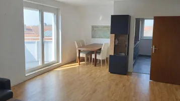 Helles Wohn- und Esszimmer mit Holzboden und Zugang zu einem sonnigen Balkon.