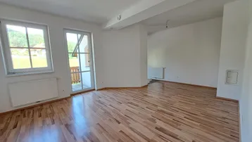 Helles Wohnzimmer mit Holzboden und Zugang zu einem Balkon, bietet viel natürliches Licht.