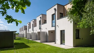 Moderne Reihenhäuser mit klaren Linien und großen Fenstern, umgeben von grünen Rasenflächen.