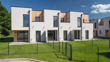 Moderne Reihenhäuser mit weißer Fassade, Holzverkleidung und kleinen privaten Gärten.