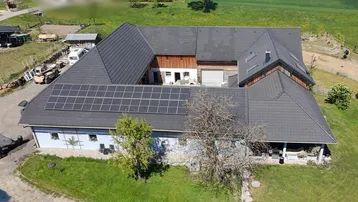 Luftaufnahme eines großen Gebäudekomplexes mit Solaranlage und weitläufigen Grünflächen.