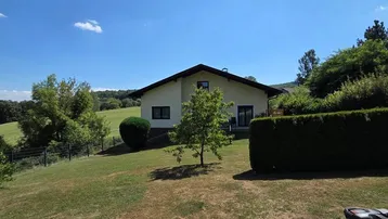 Großzügiger Gartenbereich mit Rasenfläche, Bäumen und Blick auf die umliegende Landschaft.