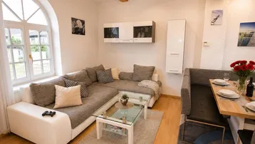 Gemütlicher Wohn-Essbereich mit Ecksofa, Holzbalken und einem Bogenfenster, ideal zum Entspannen.