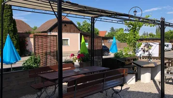 Gemütlicher Außenbereich mit Pergola, Holztischen und Bänken, ideal für entspannte Stunden im Freien.