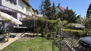 Gepflegter Gartenbereich mit Rasenfläche, Pflanzen und einer Terrasse mit Sitzgelegenheiten.