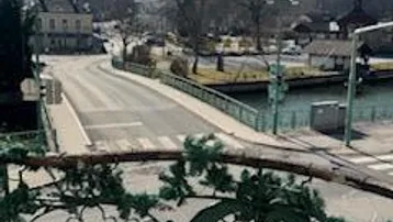 Panoramablick auf eine Brücke, einen Fluss und die umliegenden Berge von einem Balkon.