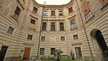 Historische Fassade eines Gebäudes mit einem geschwungenen Innenhof und vielen Fenstern.