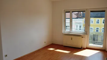 Heller Raum mit großem Fenster, Zugang zum französischen Balkon und Laminatboden.
