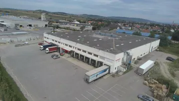 Luftaufnahme eines großen Industriegebäudes mit mehreren Laderampen und einem weitläufigen Parkplatz.