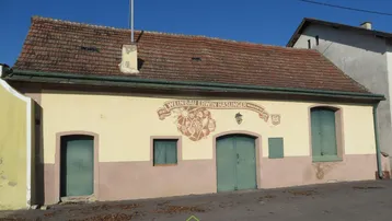 Altes Gebäude mit verputzter Fassade, Ziegeldach und historischen Holztüren.