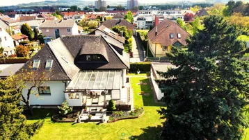 Luftaufnahme des Hauses mit großem Garten, Wintergarten und umliegender Wohnbebauung.