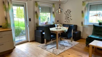 Heller Essbereich mit Holzboden, gemütlicher Sitzecke und Zugang zur Terrasse.