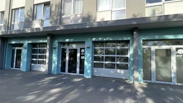 Ansicht der Gebäudefassade mit mehreren Eingängen und Garagentoren im Erdgeschossbereich des modernen Gebäudes.