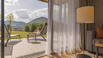 Helles Wohnzimmer mit Zugang zur Terrasse und weitem Blick auf die umliegende Berglandschaft.
